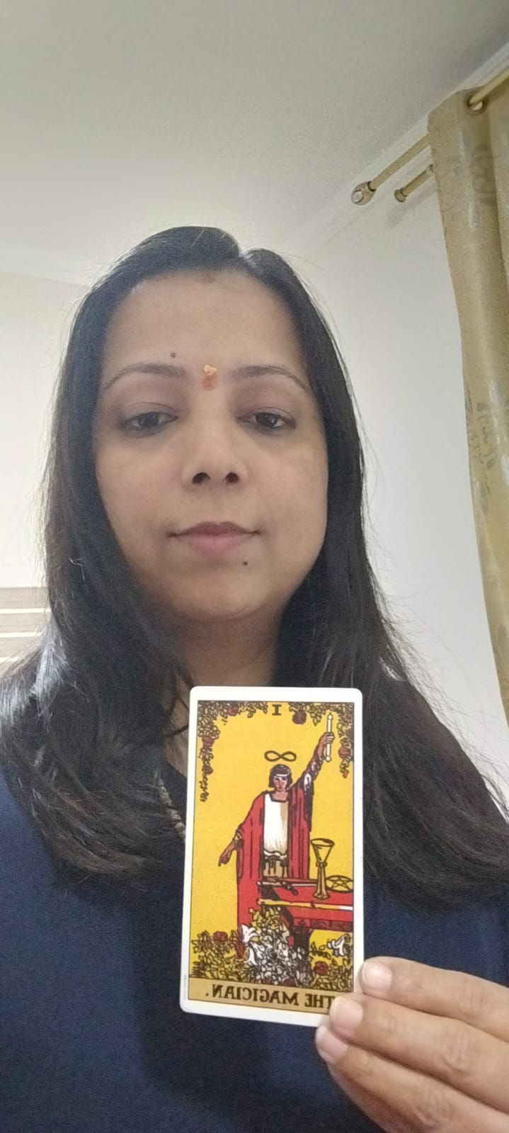 Yaashashrie holding The Magician Tarot card
