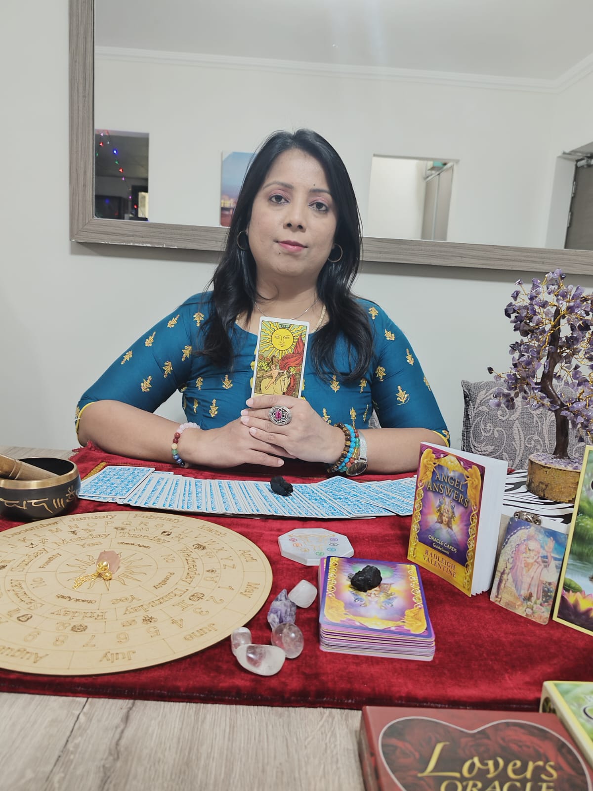 Yaashashrie holding The Sun Tarot card over reading table